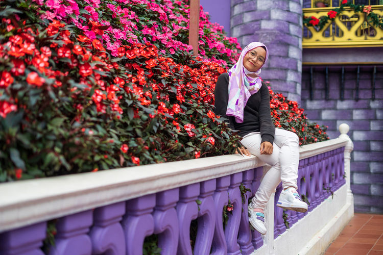 Low angle view of woman sitting on railing