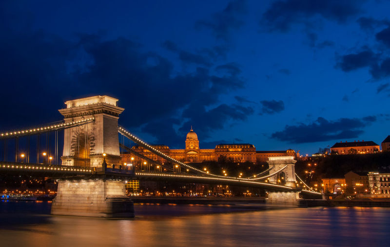 Illuminated bridge over river at night