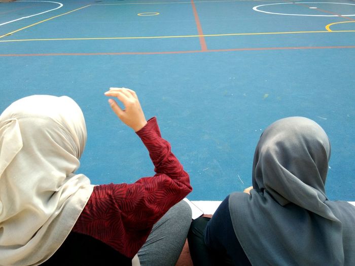 Rear view of female friends wearing hijab on court