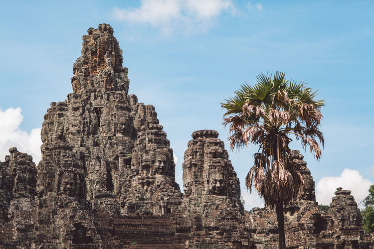 Low angle view of temple and palm trees against sky