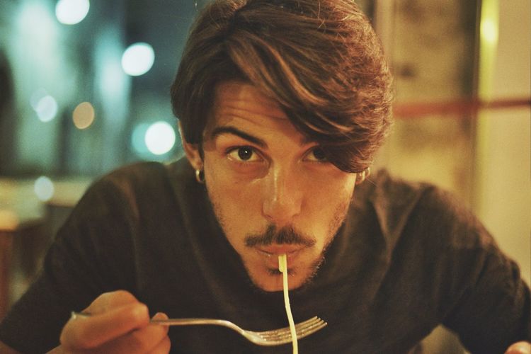 Close-up of young man having spaghetti at restaurant