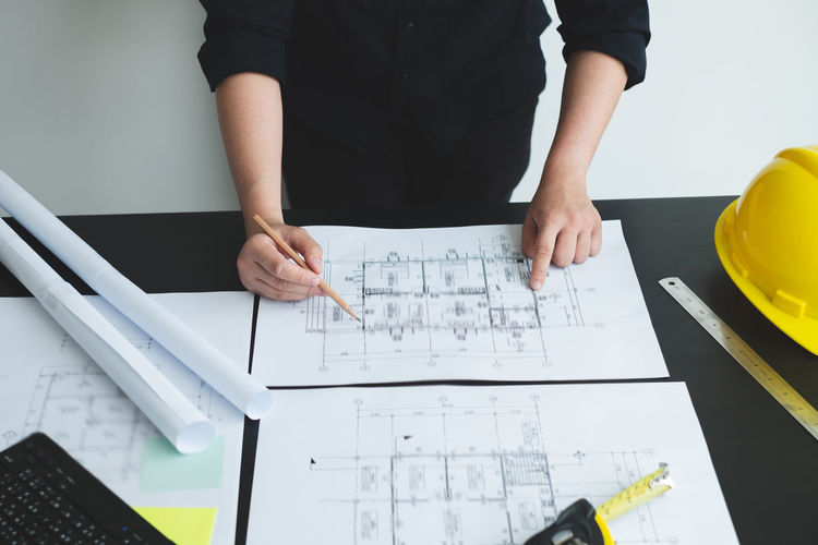 Midsection of architect working on blueprint
