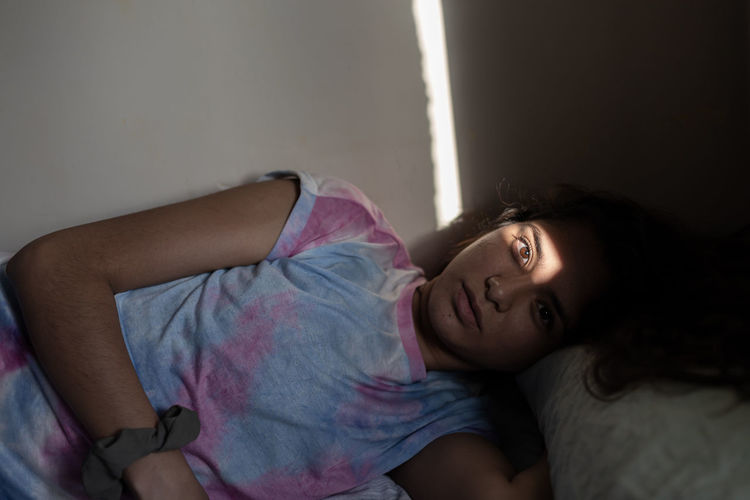 Portrait of young woman sitting on bed at home