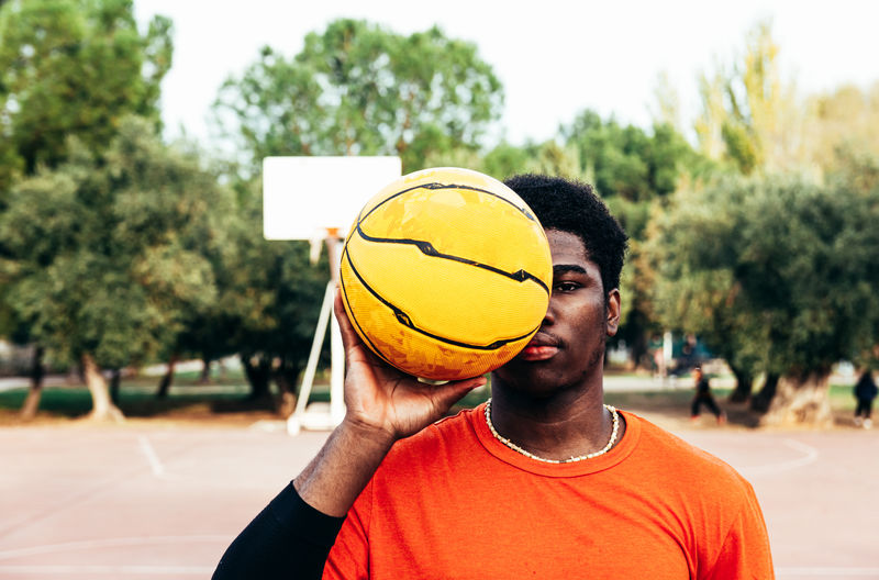 Portrait of young man holding basketball at court