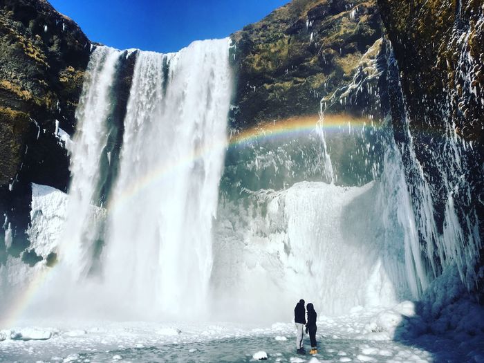 People standing by waterfall in forest