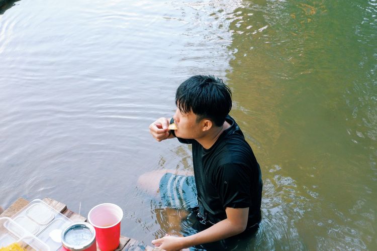High angle view of man eating food in lake