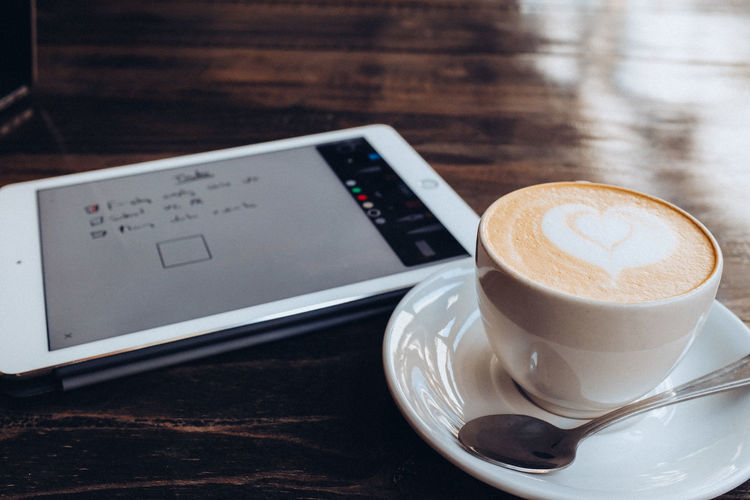 Close-up of coffee in cup by digital tablet on table