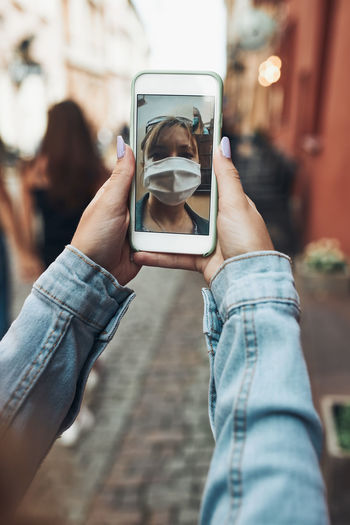 Young woman having video call talking while walking downtown chatting with friend wearing a mask