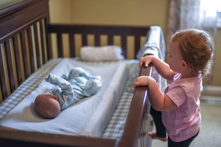 Baby girl looking newborn boy lying in crib