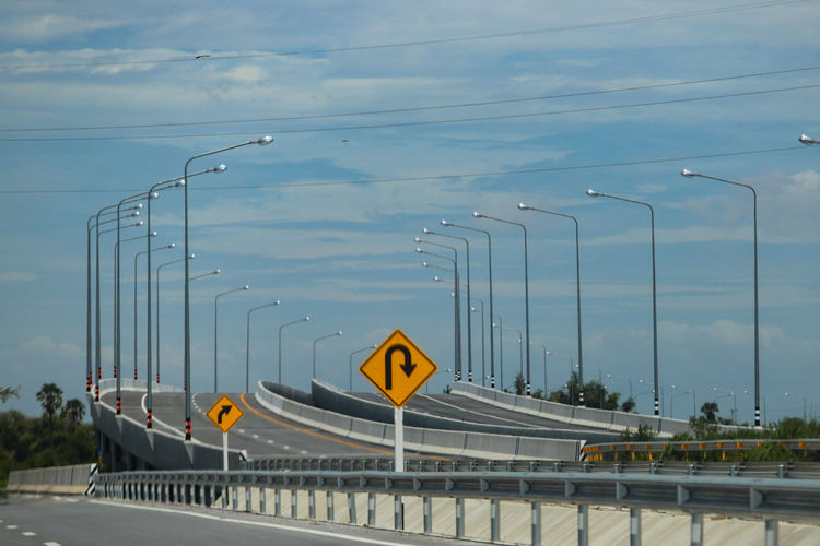 Road sign on bridge against sky