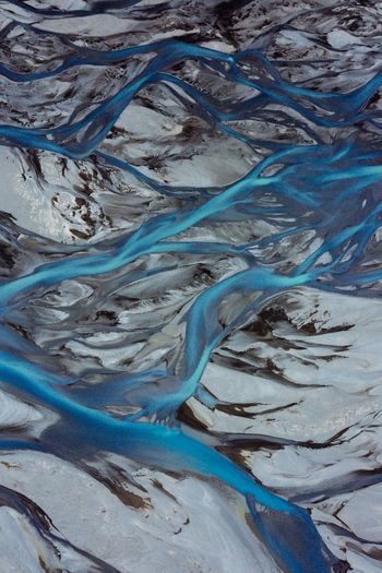 Aerial view of streams flowing on snow covered landscape