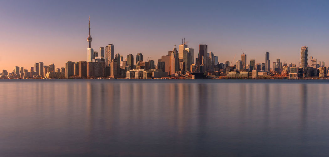 Sea by buildings against sky in city