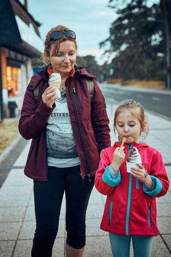 Mother and her daughter enjoying ice cream walking through town afternoon