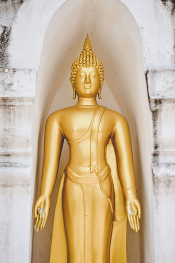 Close-up of golden buddha statue in niche