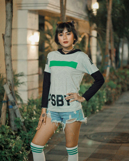 Portrait of young woman standing against trees