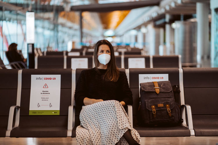 Woman wearing mask sitting at airport