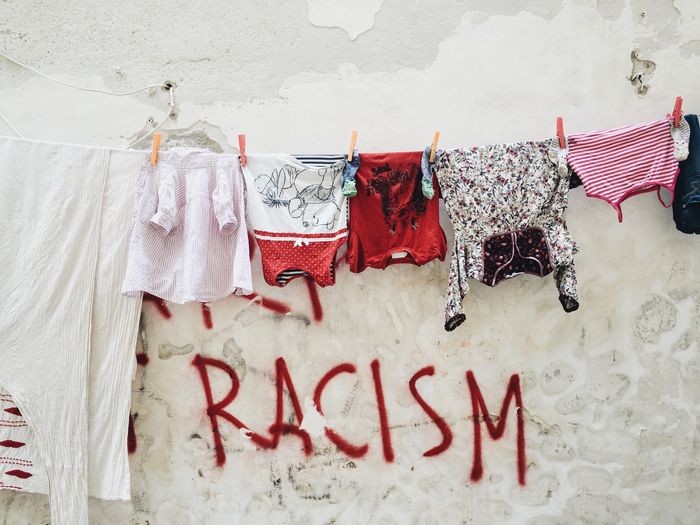 Laundry hanging from clothesline against racism text on wall