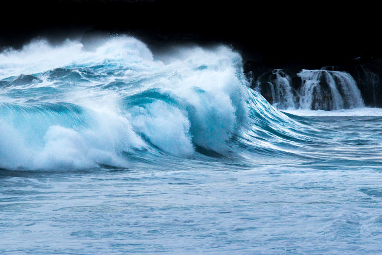 Waves splashing in sea against blue sky