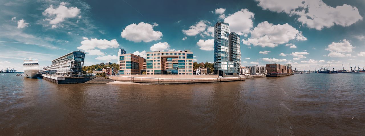 Panoramic view of buildings by river against sky