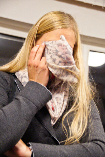 Sad woman covering face with napkin at home