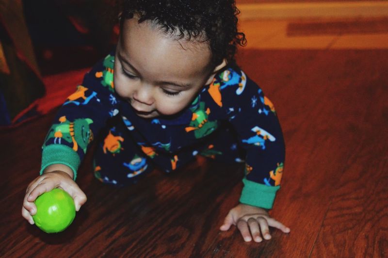 Close-up of baby boy playing with ball on hardwood floor