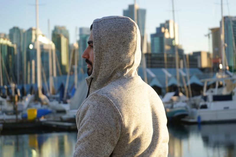 Man in hooded shirt at harbor in city