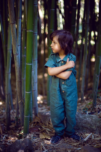 Side view of boy standing in forest
