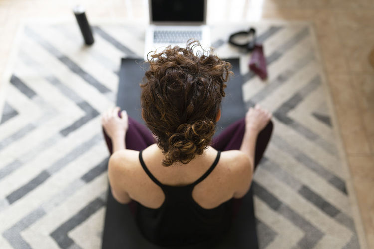 Woman on exercise mat practicing yoga at home