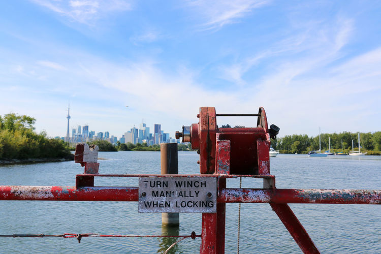 Cable winch with sign by sea against cn tower in city