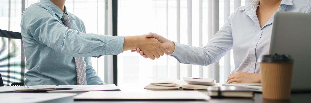 Midsection of businessmen shaking hands in office