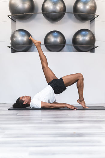 Young man practicing pilates on mat at yoga studio
