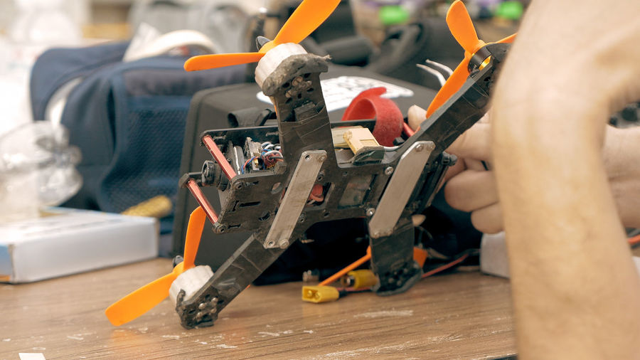 Cropped hands of man repairing quadcopter at workshop