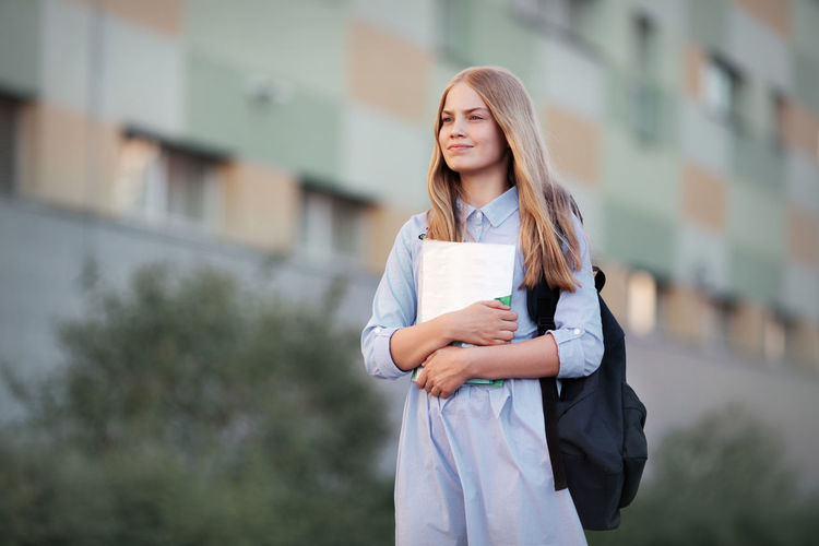 First day at high school. girl portrait of beautiful teen model long blonde hair standing outside