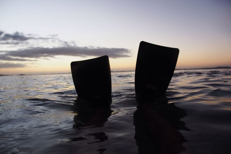 Close-up of mobile phone at beach against sky during sunset