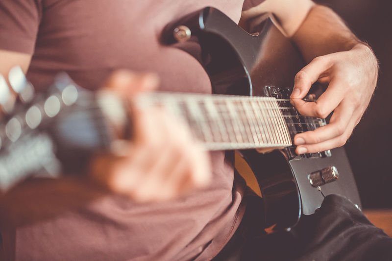 Midsection of man playing guitar