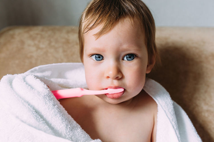 Close-up portrait of cute girl brushing teeth at home