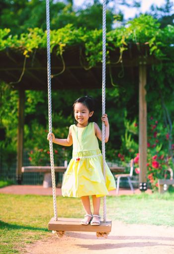 Happy girl standing on rope swing