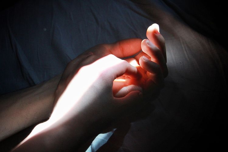 Close-up of person hand on illuminated lamp