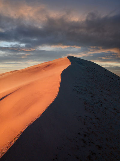 Scenic view of dunes against sky during sunset