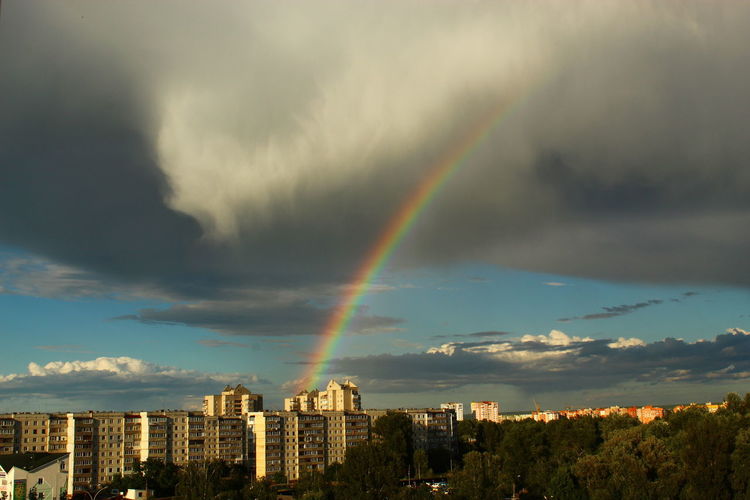 Rainbow over buildings in city against sky