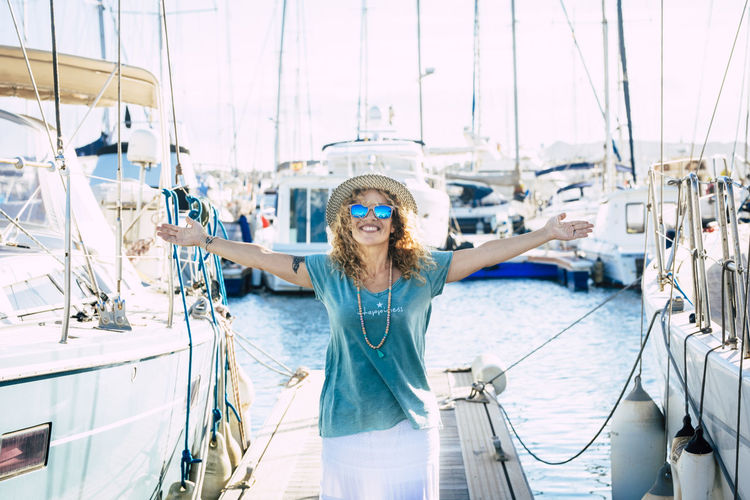 Portrait of woman standing against boats in water