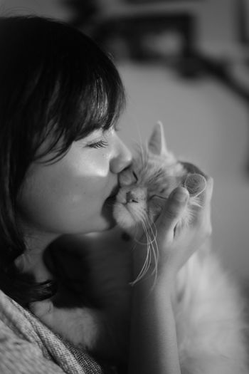 Woman kissing cat at home