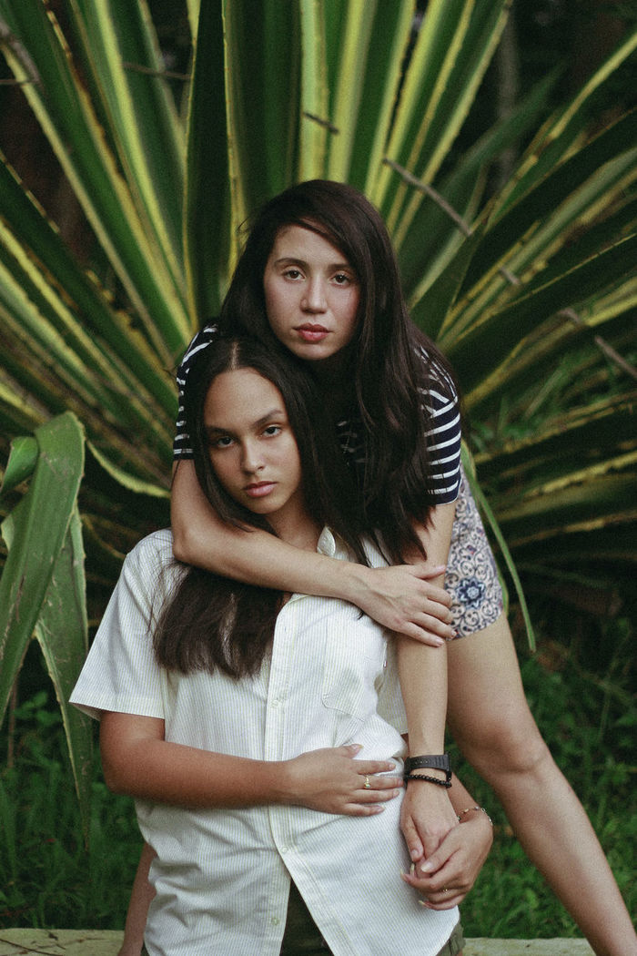 Portrait of two sisters standing against plants