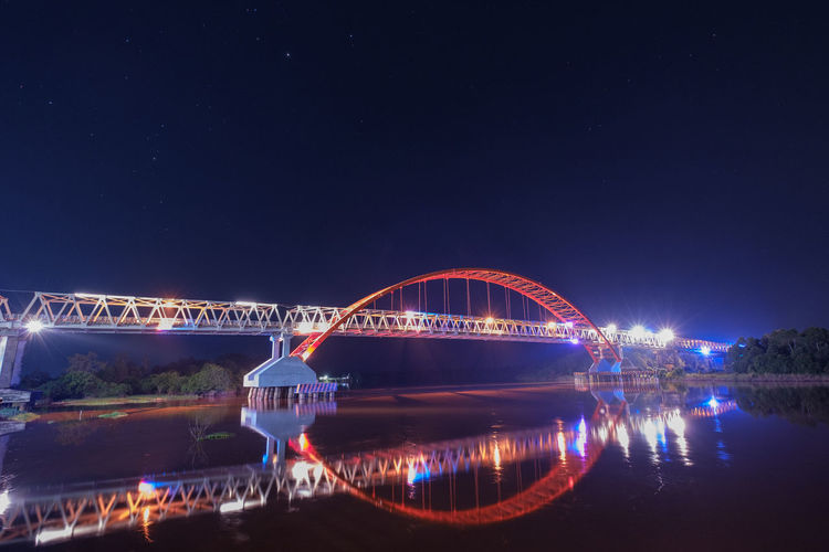 Illuminated arch bridge over river at night