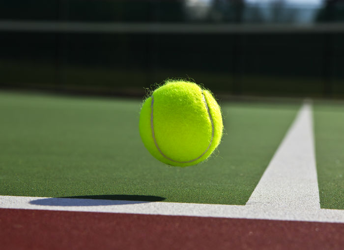 Tennis ball in mid-air over corner marking at court