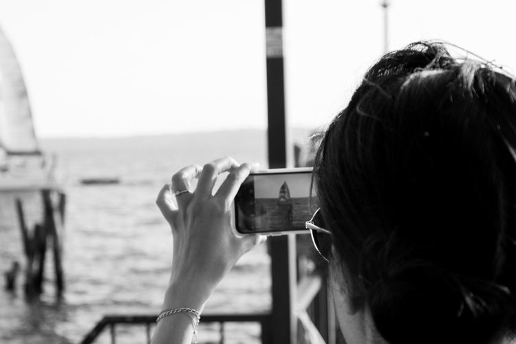 Cropped image of woman photographing through smart phone while travelling in boat