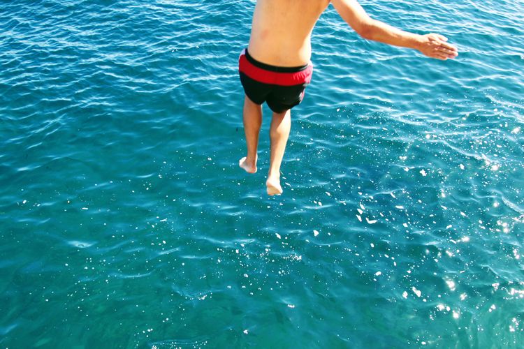 High angle view of shirtless man diving in sea on sunny day