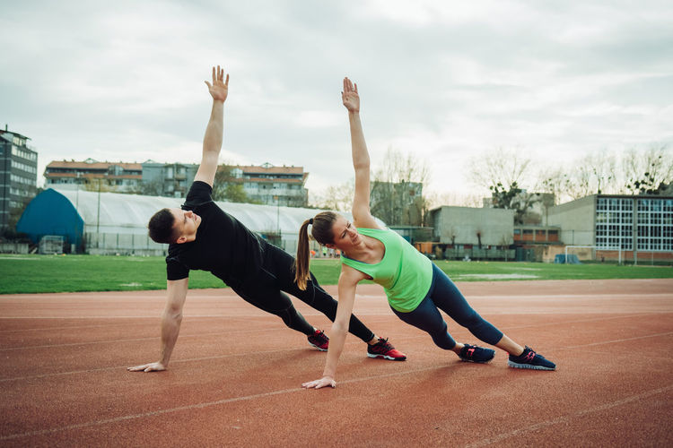 Full length of man and woman exercising on sports track