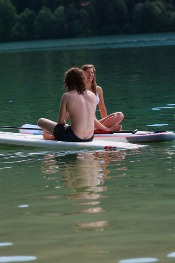 Full length of shirtless man sitting in lake