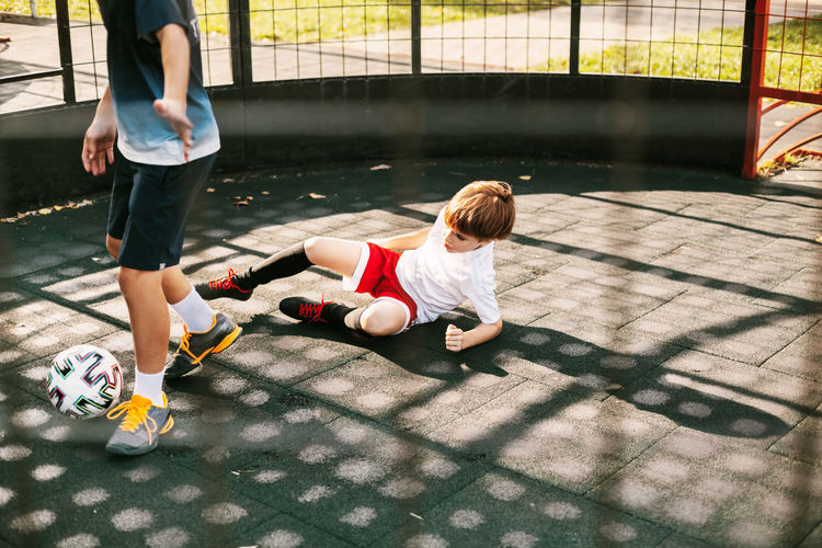 High angle view of brothers playing soccer in playground